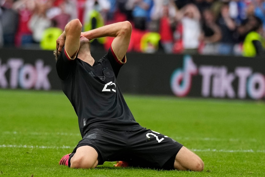 Thomas Mueller on his knees with his head in his hands. 