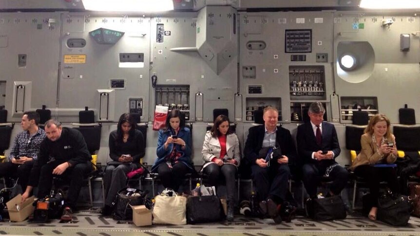 Press-gallery journalists work on their phones from an Air Force C-7 Globemaster plane