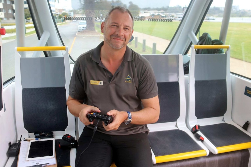 Dave the driver of the RAC's driverless bus holding the controller he can use if he needs to control the bus.