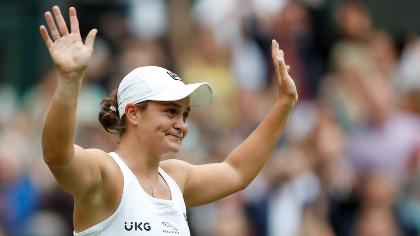 Ash Barty waves triumphantly to the crowd after winning Wimbledon