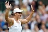 Ash Barty waves triumphantly to the crowd after winning Wimbledon