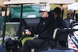 Donald Trump waves as he plays golf.
