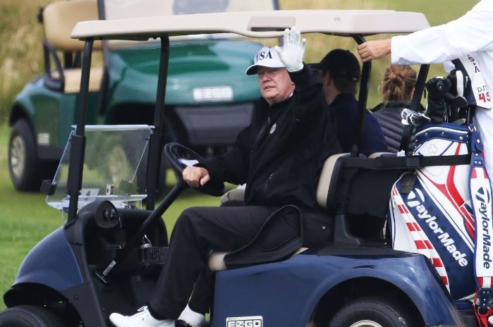 Donald Trump waves as he plays golf.