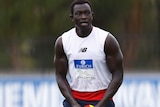 Majak Daw holds a football during a Demons training session