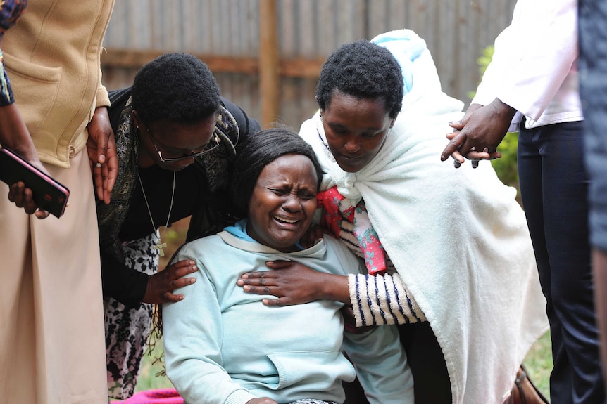 Woman collapses in grief after, with people comforting her