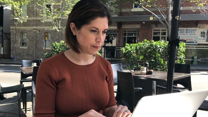 Angela Thompson works on a laptop at a cafe.