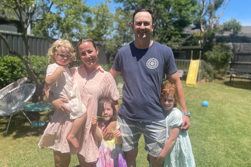 A family of five standing in a backyard