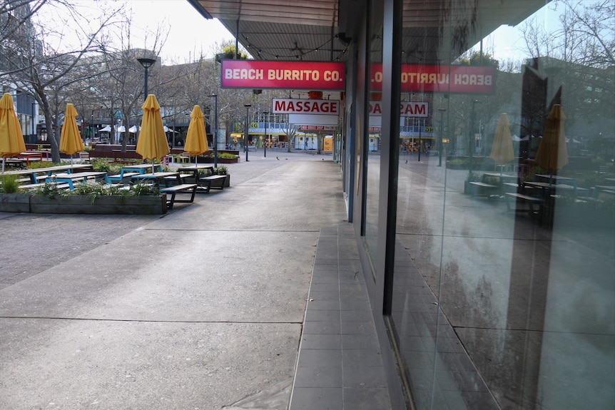 An empty street in a city centre with all shopfronts closed.