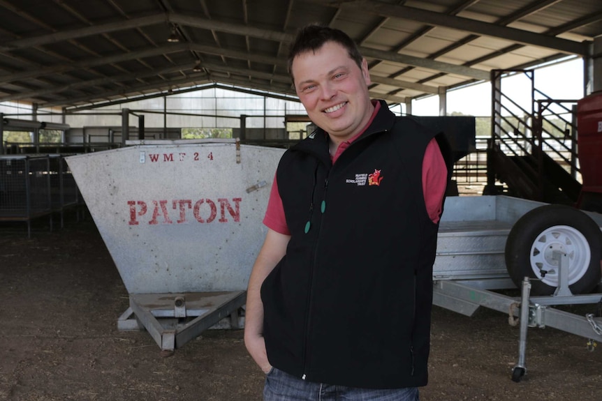 Man with one arm stands in farm shed