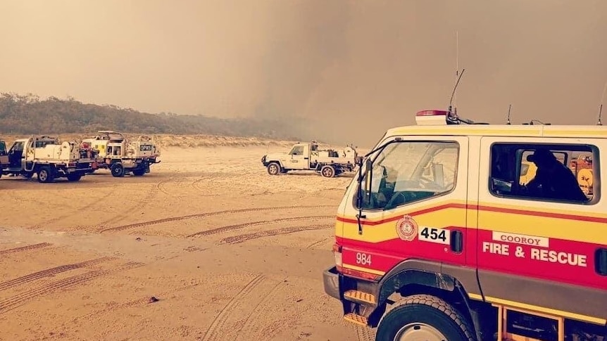 Fire truck on beach with smoke.