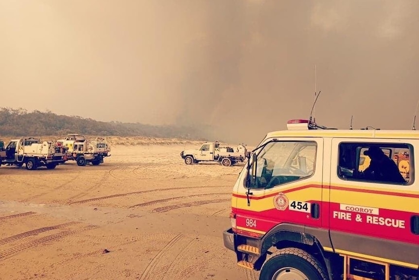 Fire truck on beach with smoke.