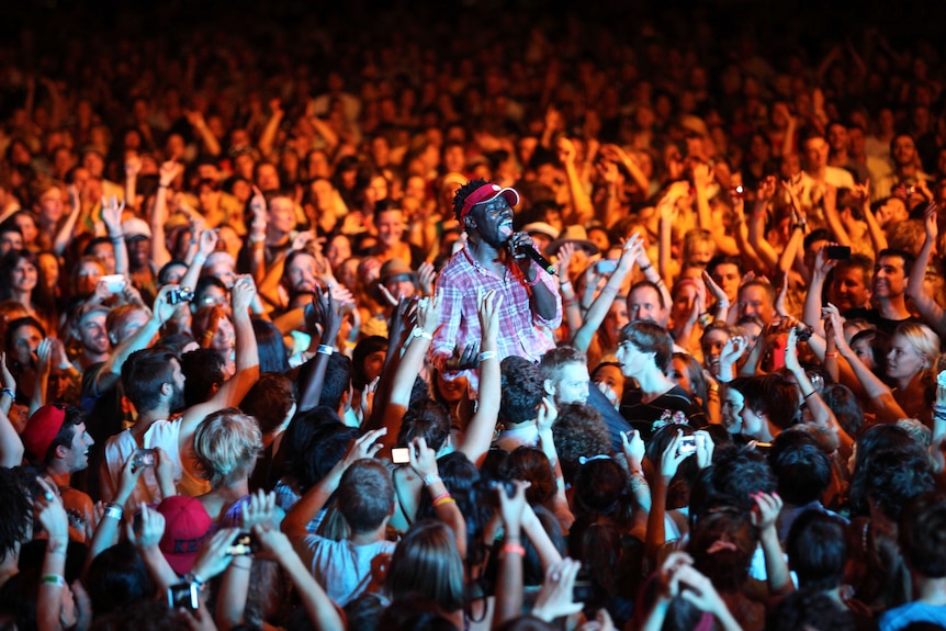 A man sings into a microphone from among the audience a night. 