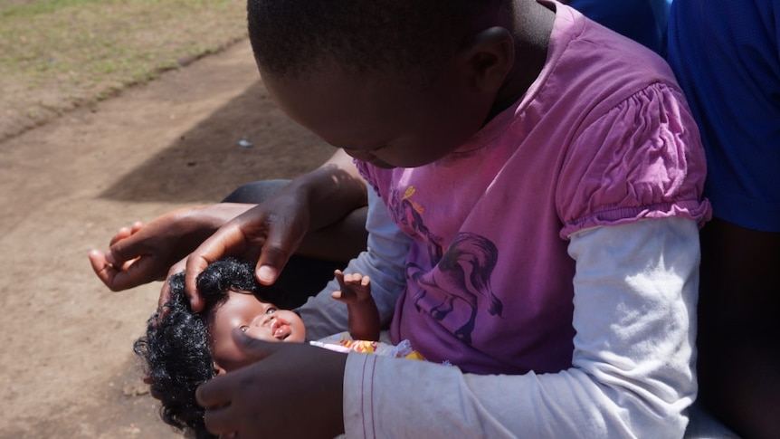 Young girl with brown skin holds a brown-skinned baby doll