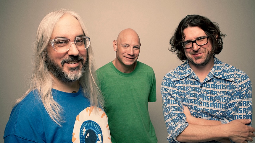 Three members of the band Dinosaur Jr stare into the camera, smiling