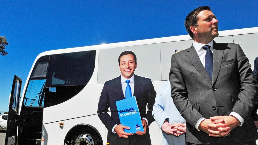 Matthew Guy stands in front of a bus bearing his image and the words 'Get back in control'.