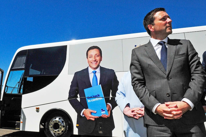 Matthew Guy stands in front of a bus bearing his image and the words 'Get back in control'.