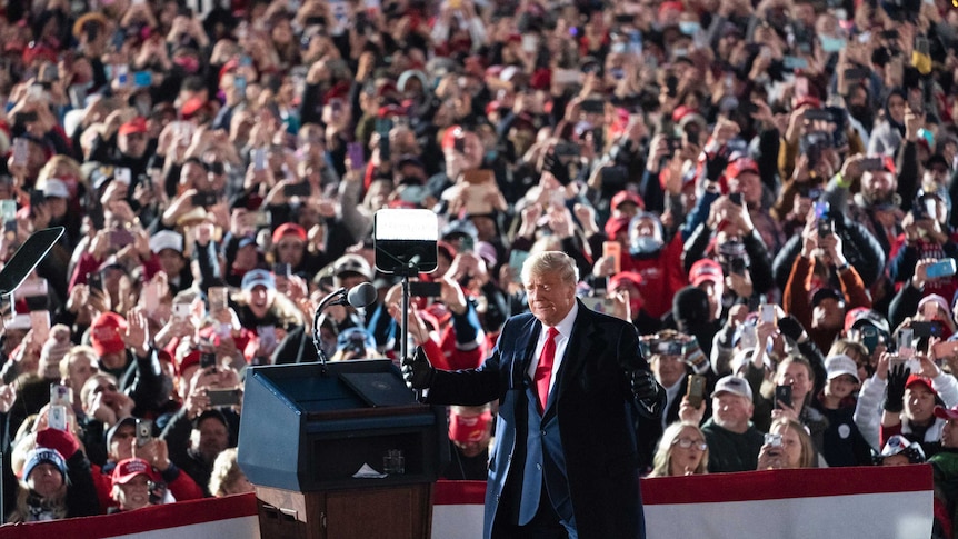 President Donald Trump stands at a podium in front of a big crowd at a US election rally in Pennsylvania.