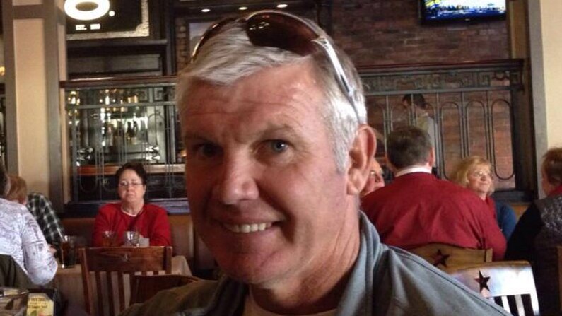 Danny Frawley smiles at the camera in a restaurant.