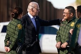 Mr Biden speaks with a man in unform and has his hand on his shoulder. 