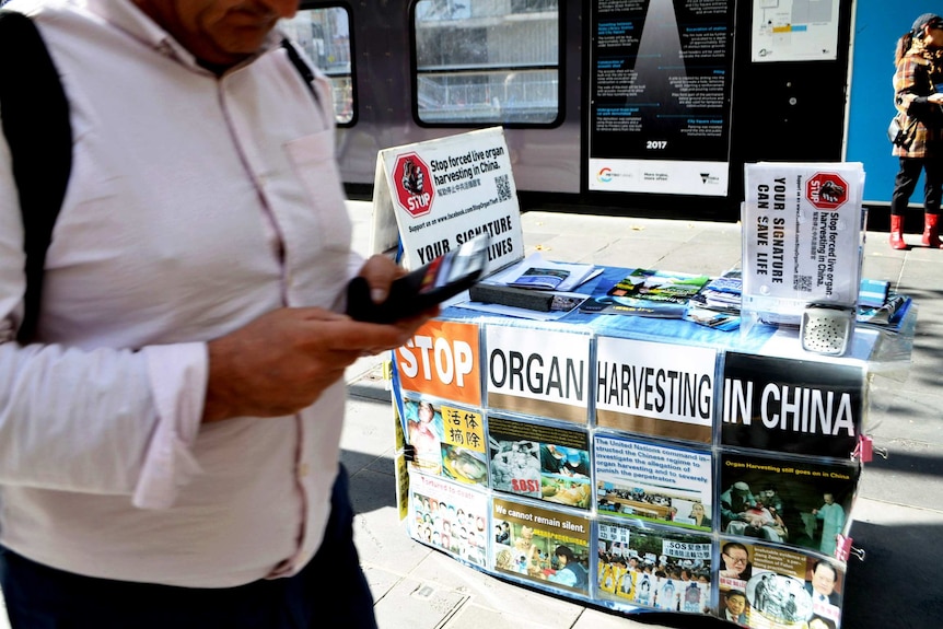 A folding table full of campaign pamphlet is right in the centre of the image while a man was passing by it appearing in left.