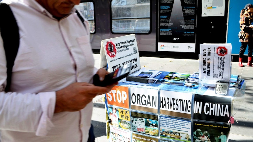 A folding table full of campaign pamphlet is right in the centre of the image while a man was passing by it appearing in left.