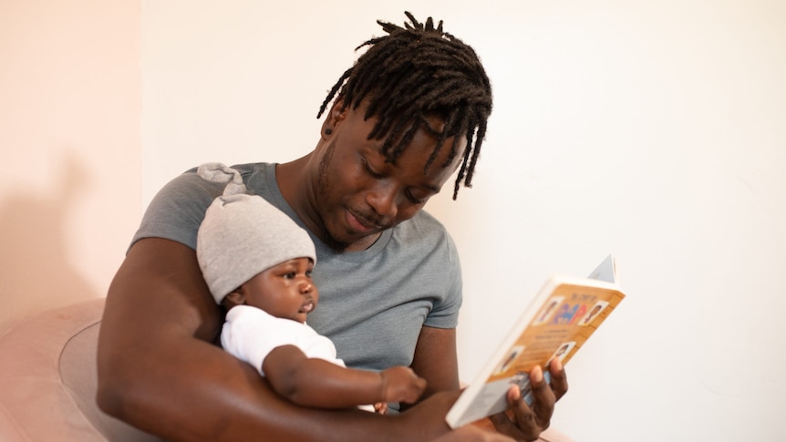 A young father reading to his baby.