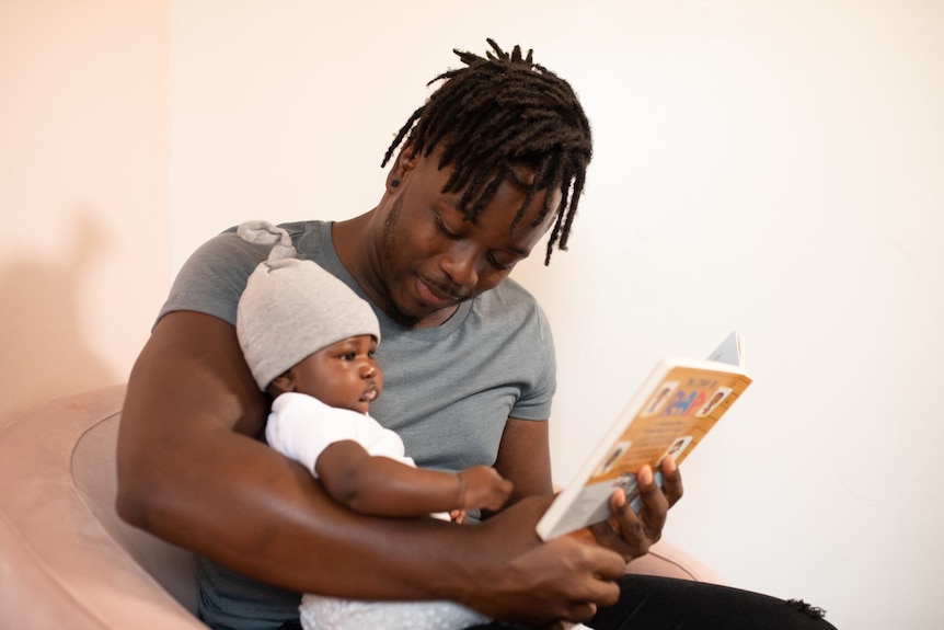A young father reading to his baby.