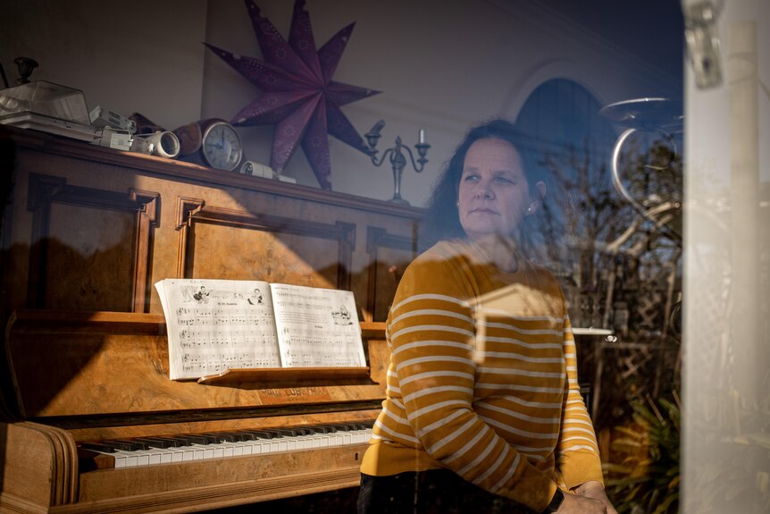 Kylee Pearn looks out a window as she sits next to a piano.