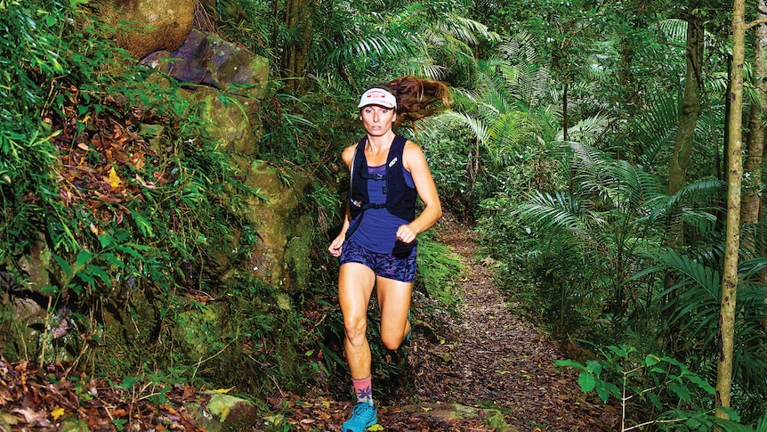 woman running in a forest wearing athletic gear 