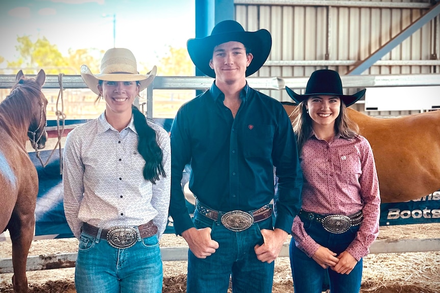 A woman in a white shirt and cowboy hat, a man with a black shirt and cowboy hat and young woman with pink shirt and cowboy hat 