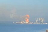 Far away view of ship on fire.