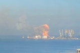 Far away view of ship on fire.