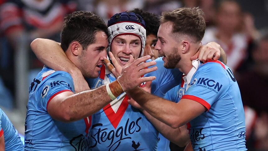 Three men celebrate after scoring a try in a rugby league match