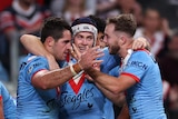 Three men celebrate after scoring a try in a rugby league match