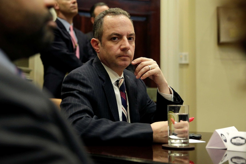 Reince Priebus sits at a meeting table listening
