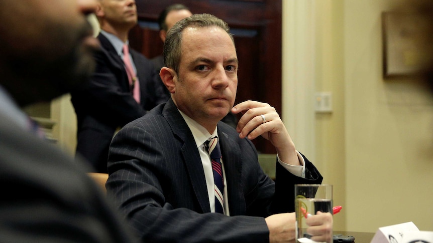 Reince Priebus sits at a meeting table listening