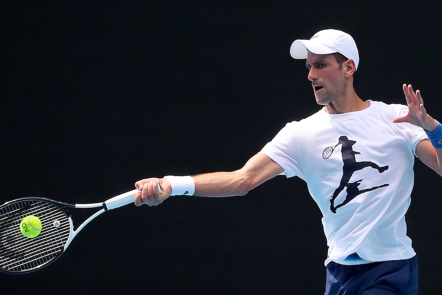 Novak Djokovic is mid-swing with his raquet to hit a tennis ball at Melbourne Park.