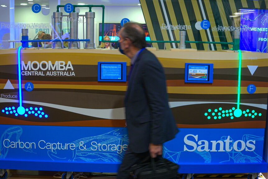 A man walks past a Santos display about carbon capture at COP26.