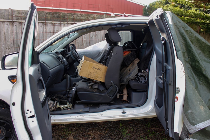 A photo of the inside of the ute with engine parts strewn over the passenger seat and floor.