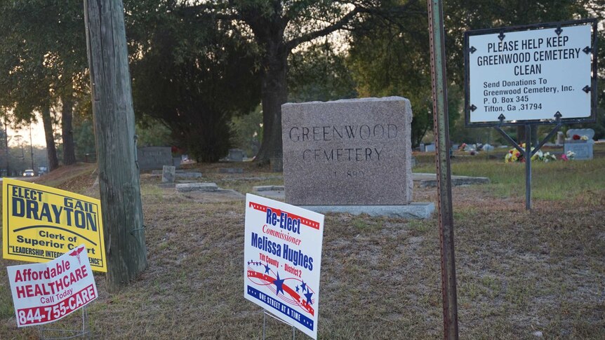 A sign for 'affordable healthcare' sits outside a cemetery