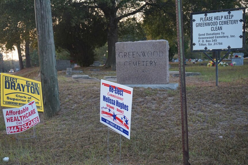 A sign for 'affordable healthcare' sits outside a cemetery