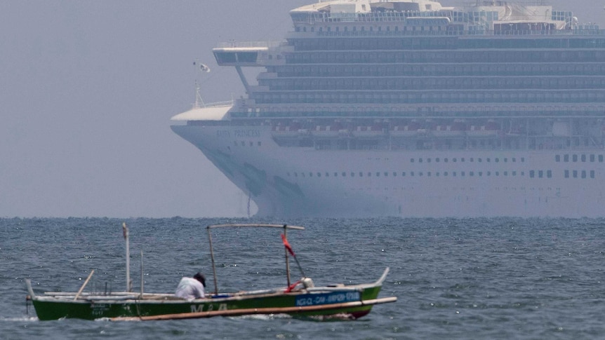 A small fishing boat with a man in it floats in front of a large white cruise ships in the ocean