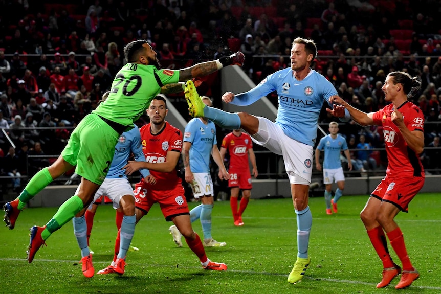 Paul Izzo, left, wearing green, dives to punch the ball clear from Rostyn Griffiths who stands with his leg stretched out