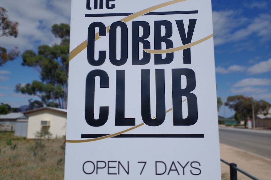 A picture of the Cobdogla Club on a street showing which way for patrons to come. 