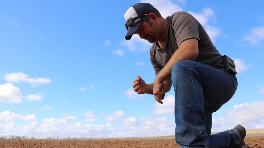 A man kneeling in the dirt.
