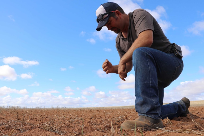 A man kneeling in the dirt.