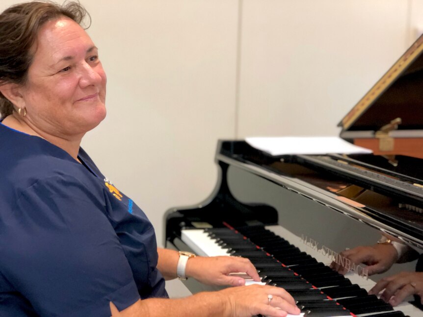 Female nurse sitting at a piano playing.