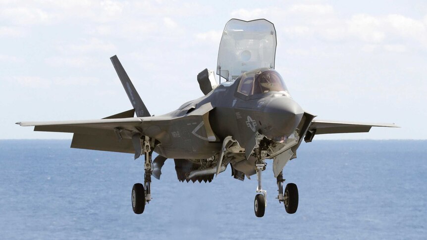 A US military F-35B fighter jet is photographed approaching an aircraft carrier in the western Pacific.