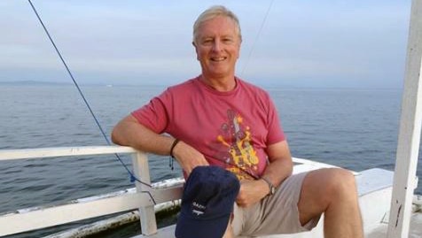 Roger Hussey sitting down with the ocean in the background.