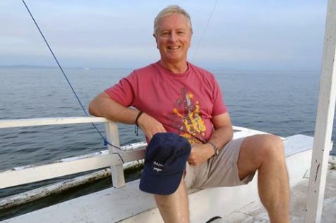 Roger Hussey sitting down with the ocean in the background.